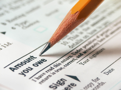 A pencil resting on an IRS tax return at the amount-you-owe line